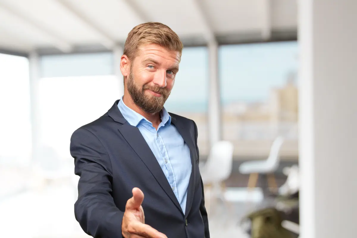 Smugly smiling businessman extending hand for handshake